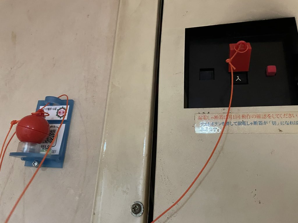 分電盤のブレーカーの横に付けた感震ブレーカーと、つまみにつながるひも